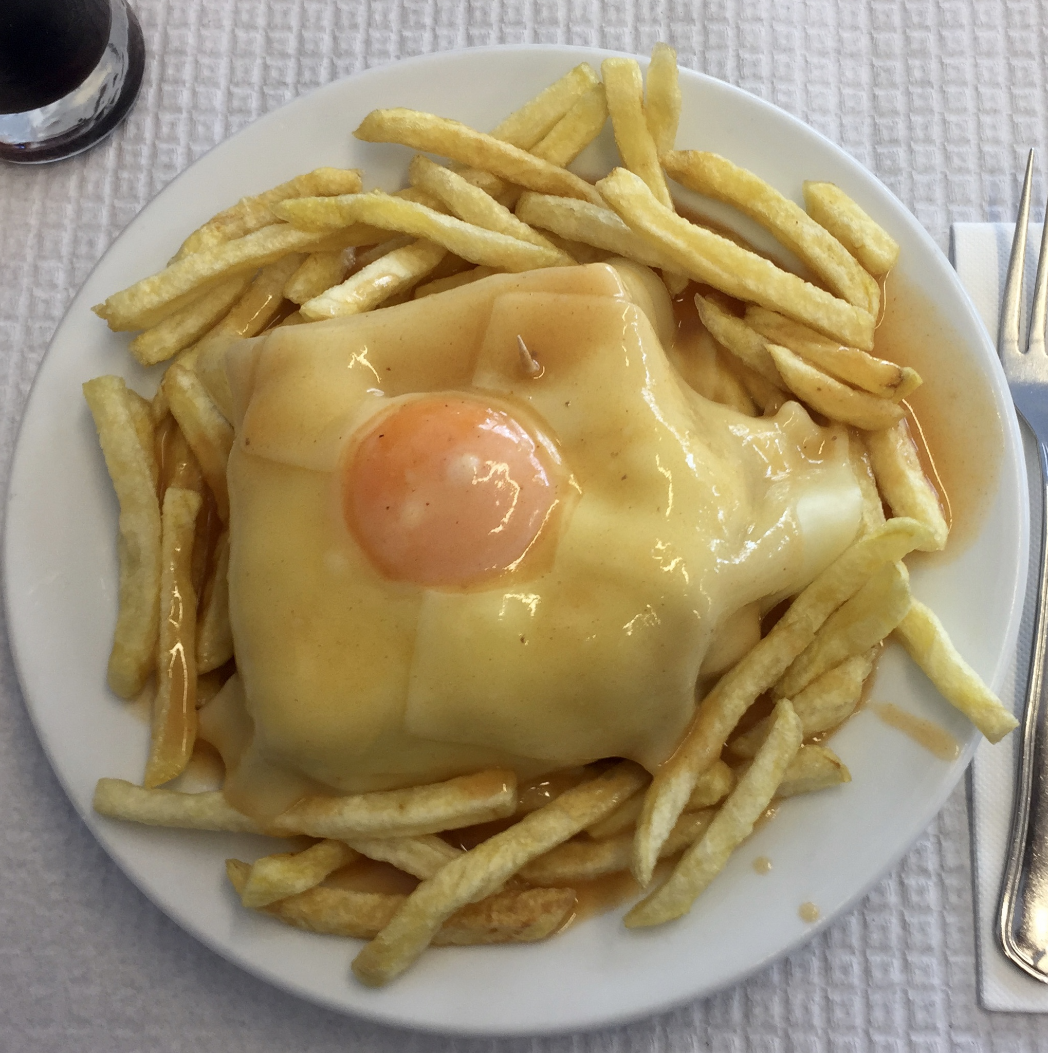Classic francesinha: bread, cured meats, melted cheese and sauce, served with fries